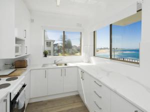 a white kitchen with a view of the ocean at Waterfront Unit 2 in The Entrance