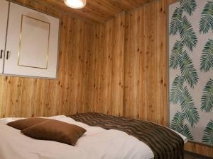 a bedroom with wood paneled walls and a bed at ホテルLambie in Tōgane