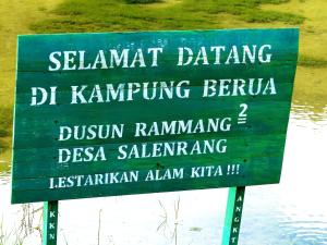 a green sign in front of a body of water at Rammang Rammang Kampoeng Karst Family Homestays in Kasijala