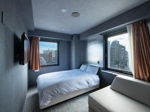 um quarto com uma cama e uma janela em EN HOTEL Hamamatsu em Hamamatsu