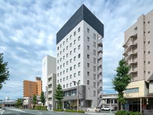 a tall white building with a black roof at EN HOTEL Hamamatsu in Hamamatsu