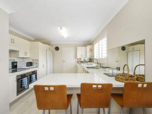 a kitchen with a large white island with chairs at 44 Oaks Avenue in Long Jetty