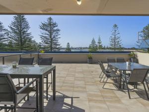 a patio with two tables and chairs and trees at Lakeshore Apartments Unit 6 in The Entrance