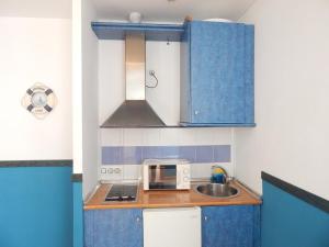 eine kleine Küche mit blauen Schränken und einem Waschbecken in der Unterkunft Apartahotel Playa Conil in Conil de la Frontera