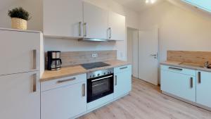 uma cozinha com armários brancos e um forno com placa de fogão em Alte Schule Spittelstein 1OG rechts em Rödental