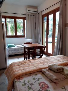 um quarto com uma cama, uma mesa e janelas em Pousada Praia Verde em Barra de Ibiraquera