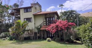 a house with pink flowers in front of it at Pousada Praia Verde in Barra de Ibiraquera
