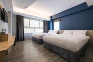 a hotel room with two beds and a blue wall at Sparrow Hotel in Taichung