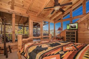 Dormitorio en cabaña de madera con cama y TV de pantalla plana en Brown Bear Lodge -4 Bed, 4 Bath huge Gameroom and mountain views, en Sevierville