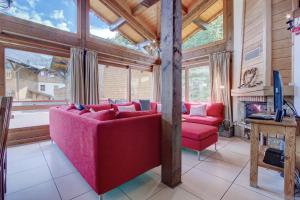 a living room with a red couch and a tv at Chalet Madeleine in Morzine