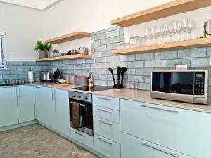 uma cozinha com armários brancos e um micro-ondas em The Anchor, Luxury living for 2 with sea view and Jacuzzi em Gordonʼs Bay
