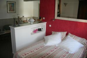 1 cama con 2 almohadas y pared roja en Une Chambre à la Campagne en Nantes