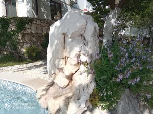 a rock fountain next to a swimming pool with flowers at KATY&MLADEN in Baška