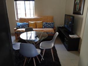 a living room with a table and chairs and a couch at Aloha Lodge 2 Bedroom Apartment near Menlyn Sleeps 4 in Pretoria