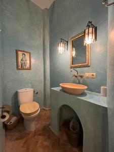 a bathroom with a toilet, sink and mirror at Riad Baladin in Essaouira