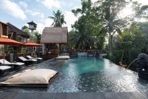 a swimming pool with pillows and chairs in a resort at Vije Boutique Resort & Spa in Ubud