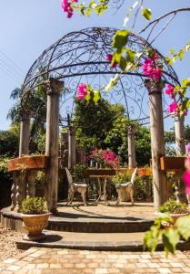 a gazebo with a table and chairs and flowers at La Casa Nostra Villa Rose Garden Amore in Hillcrest