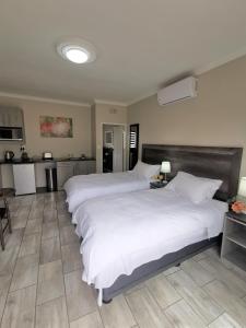 a large bedroom with two beds and a kitchen at Up21 Guest House in Boksburg