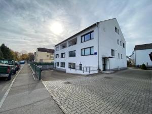 un bâtiment blanc dans une rue avec un parking dans l'établissement LUXOMES - Modern Design Apartments - Ingolstadt Central, à Ingolstadt