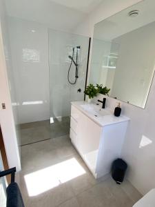 a bathroom with a white sink and a shower at Flower Farm Tamborine Mountain in Mount Tamborine