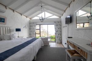 a bedroom with a large bed and a tv in it at Dutton's Cove Guest House in Herolds Bay