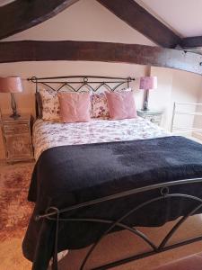 a bedroom with a large bed with pink pillows at Longbridge Cottage in Shepton Mallet