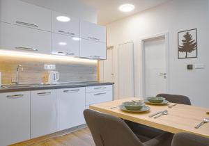 a kitchen with white cabinets and a wooden table at TATRYSTAY Apartment Sankt Bernard in Smokovce