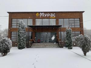 a building with snow in front of it at Muras Hotel Karakol in Karakol