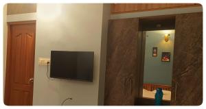 telewizor z płaskim ekranem na ścianie obok lustra w obiekcie High Island Homestay w mieście Koczin