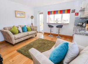 a living room with a couch and a kitchen at Meadow View at Keepers Cottage in Eaton