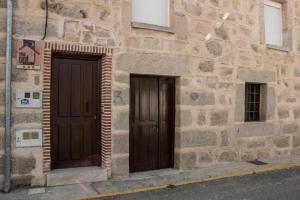 dwa drzwi na boku kamiennego budynku w obiekcie Casa Rural Paco w mieście Muñogalindo