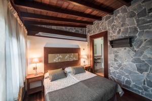 a bedroom with a bed and a stone wall at CASA RURAL EL LAGAR TENERIFE in La Orotava