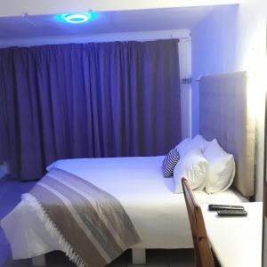 - une chambre avec un lit et un bureau avec télécommande dans l'établissement Belavista, quaint and cozy cottage in Sunwich Port, à Port Shepstone