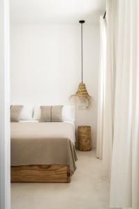 a white bedroom with a large bed and a chandelier at Meloussa Boutique Hotel in Ciutadella