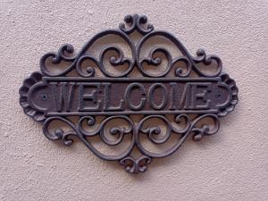 a metal welcome sign on the side of a wall at Longbridge Cottage in Shepton Mallet