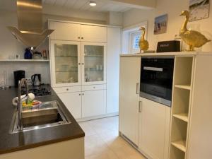 eine Küche mit weißen Schränken, einer Spüle und Enten auf der Theke in der Unterkunft Doras Hus in Nieblum