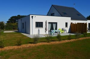 une maison blanche avec une terrasse et une pelouse dans l'établissement Gite de Ker Ravel, à Penvénan