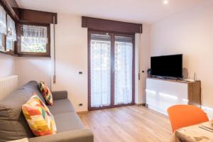 een woonkamer met een bank en een flatscreen-tv bij Casa Muffolina in Canazei