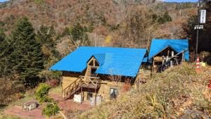 une vue de tête d'une cabane en rondins avec des toits bleus dans l'établissement pension ぽかぽか（poka poka）, à Tone