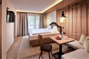 1 dormitorio con cama, mesa y sofá en Hotel Neue Post en Mayrhofen