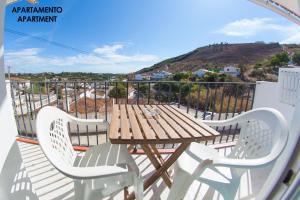 a wooden table and chairs on a balcony with a view at Apartamentos Rurales Santos in Benajarafe