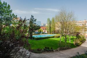 a garden with a swimming pool in a city at Los Olivos Stylish Apartments in Conde Orgaz Area in Madrid
