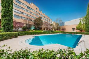 une piscine en face d'un bâtiment dans l'établissement Las Encinas Design Apartment in Conde Orgaz Area - Madrid, à Madrid