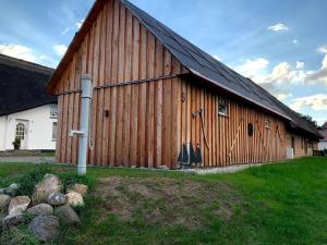 une grande grange en bois avec un toit noir dans l'établissement Fewo Fischerhus, à Zempin