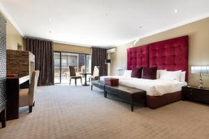 a bedroom with a large bed with a red headboard at St Andrews Hotel and Spa in Johannesburg