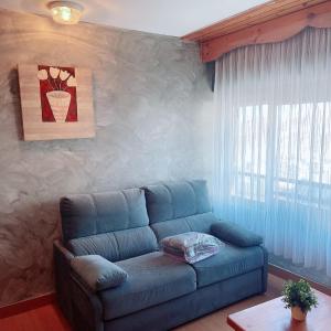 a living room with a blue couch and a window at Confortable Lake Placid in Pas de la Casa