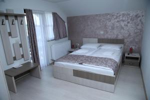 1 dormitorio con 1 cama grande y espejo en PENSIUNEA SOFIA, en Peştişani