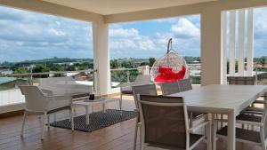 a dining room with a table and chairs on a balcony at Villa Bolati, avec piscine, jacuzzi, jardin et vue in Bonoua