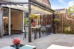 een patio met een tafel en stoelen onder een pergola bij B&B De Mansarde in Apeldoorn