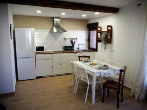 cocina con mesa con sillas y nevera blanca en La Casa de los Abuelos Valentín, en Pinilla del Valle